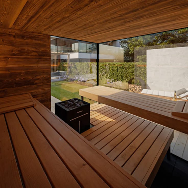 Cedar sauna interior with a rock heater and a window to a garden