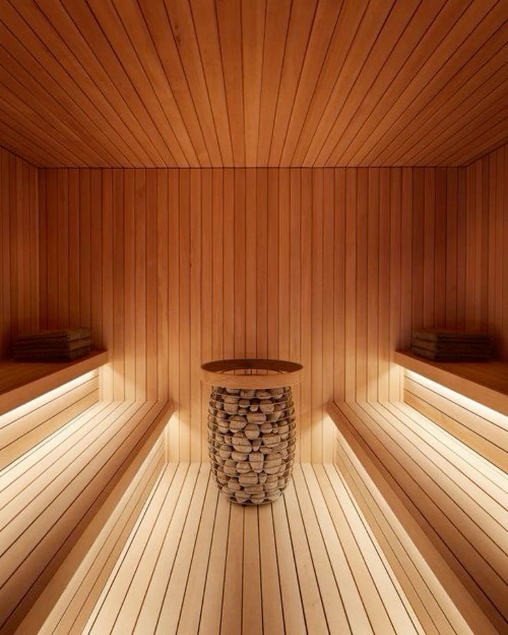 Symmetrical cedar sauna interior with facing benches and a central stone heater